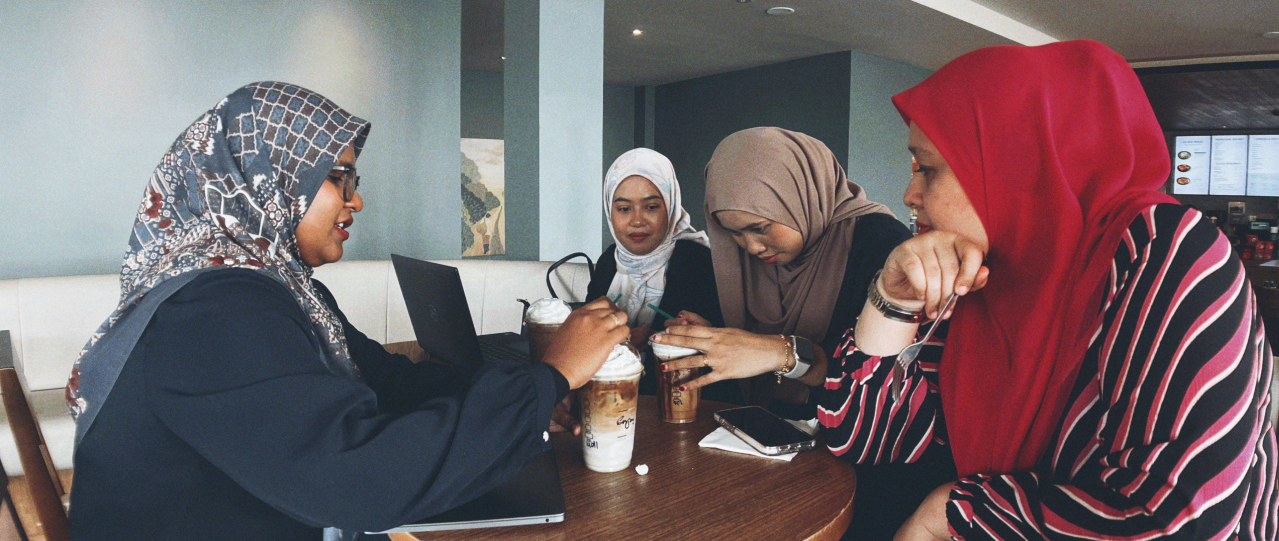 Photo of two women and a man talking in the corner of a room with modern furniture.